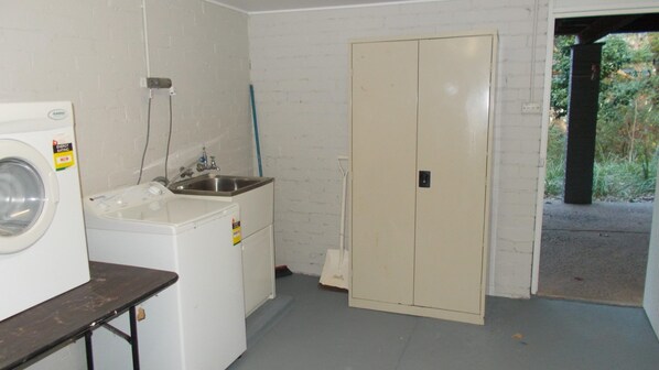 A laundry room with a washing machine, a sink, and a cabinet.