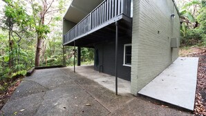 Una casa moderna con balcón, rodeada de abundante follaje.
