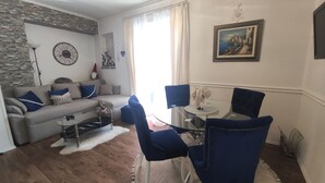 A living room with a sofa, a coffee table, and a dining area with chairs and a table. - Elitte Apartment in canter,self check in /checkout (Split)