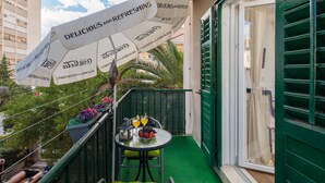 A balcony with a table, chairs, a green awning, and a potted plant. - Elitte Apartment in canter,self check in /checkout (Split)