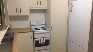 Una cocina funcional con estufa blanca, refrigerador y muebles de color beige.