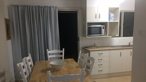 Cocina compacta con microondas, armarios y una mesa de comedor con sillas.