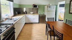 Une cuisine compacte équipée d’une cuisinière, d’un évier, d’un four à micro-ondes et d’un réfrigérateur. On y trouve également une table à manger avec des chaises.