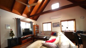 A living room with a television, sofa, and a wooden ceiling. - Kookaburra Cottage 71 Straight Hat Head (Hat Head)
