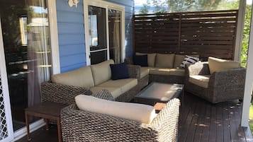 A covered patio with wicker furniture, including a sofa and armchairs, and a small table.