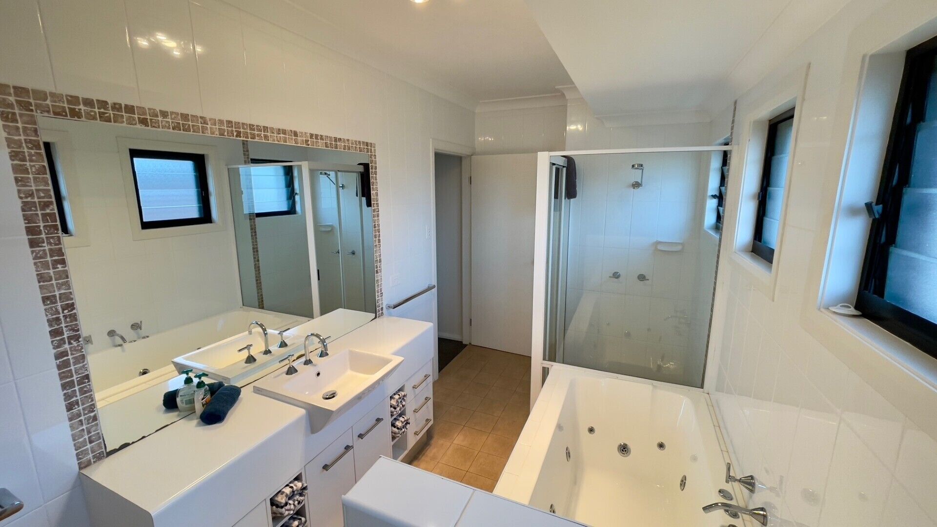 A modern bathroom with a double sink, a bathtub, and a glass-enclosed shower.