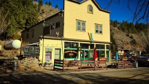 Un immeuble de deux étages abritant un café au rez-de-chaussée, reconnaissable à son auvent vert et à son panneau indicateur.