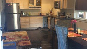Une cuisine compacte avec des meubles en bois, un réfrigérateur, un four à micro-ondes et un coin repas comprenant une chaise et une table à rayures.