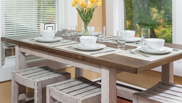 A dining table set with white plates, bowls, and glasses, accompanied by a vase of yellow tulips. - Charming apt -2 Bedroom -Close to Beach/Sleeps 6 (Ipswich)