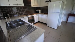Una cocina moderna con armarios blancos, un lavamanos doble, un microondas y un refrigerador.