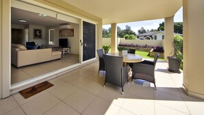 Un patio amplio con una mesa y sillas, un sofá y un televisor al fondo.