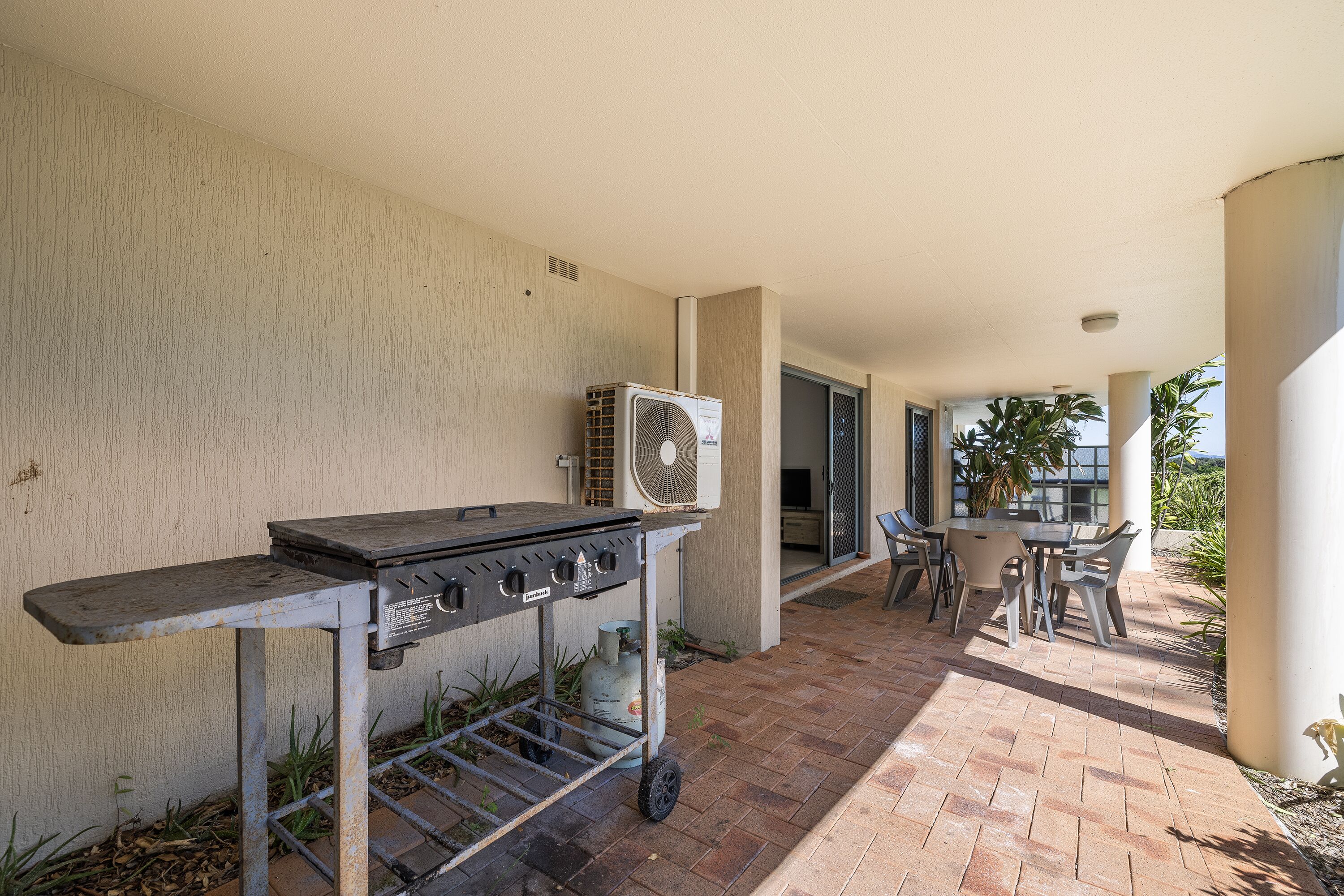 An outdoor patio with a barbecue grill, a fan, and a table with chairs.