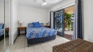 A bedroom with a bed, bedside tables, a ceiling fan, and a sliding glass door leading to an outdoor area. - All Linen Included * Center of Town * BBQ *Air Con * Private Covered Patio* (South West Rocks)