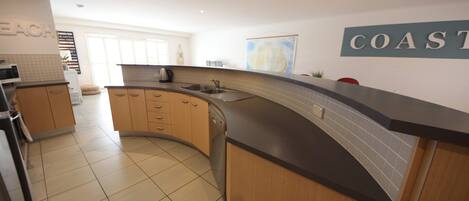 A modern kitchen with a curved island, a sink, and a backsplash.
