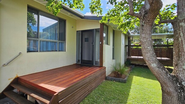 A modern house with a wooden deck, a small garden, and a tree. - Comfortable air conditioned, pet friendly holiday home with large open... (South West Rocks)