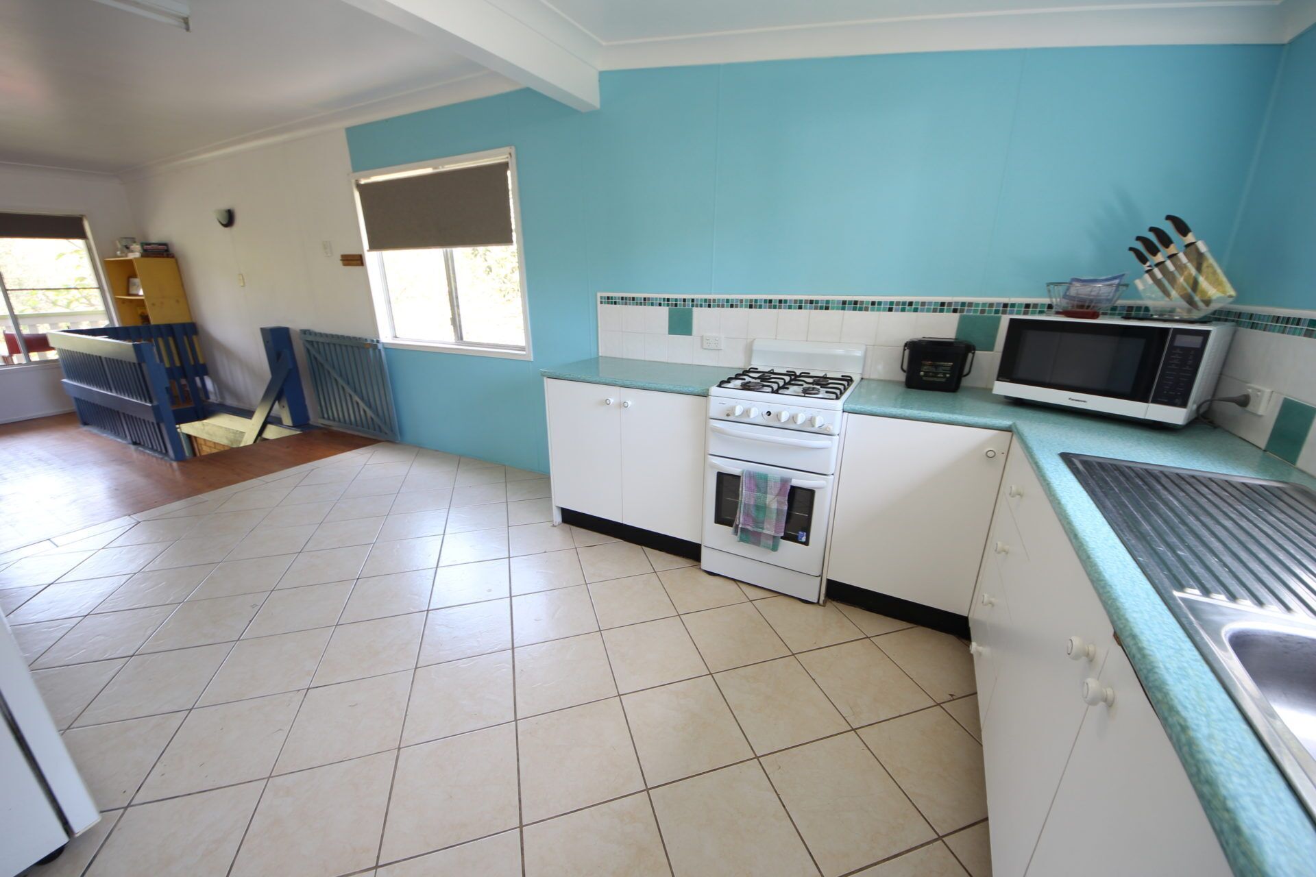 A kitchen with white cabinets, a gas stove, a microwave, and a sink.