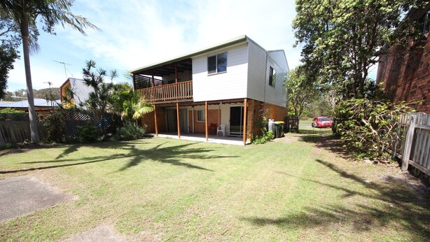 A two-story house with a covered patio and a fenced backyard.