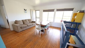 A living room with a sofa, a dining table with chairs, and a staircase.