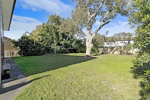 Escape to a serene outdoor oasis with a lush lawn, eucalyptus trees, and a pathway.