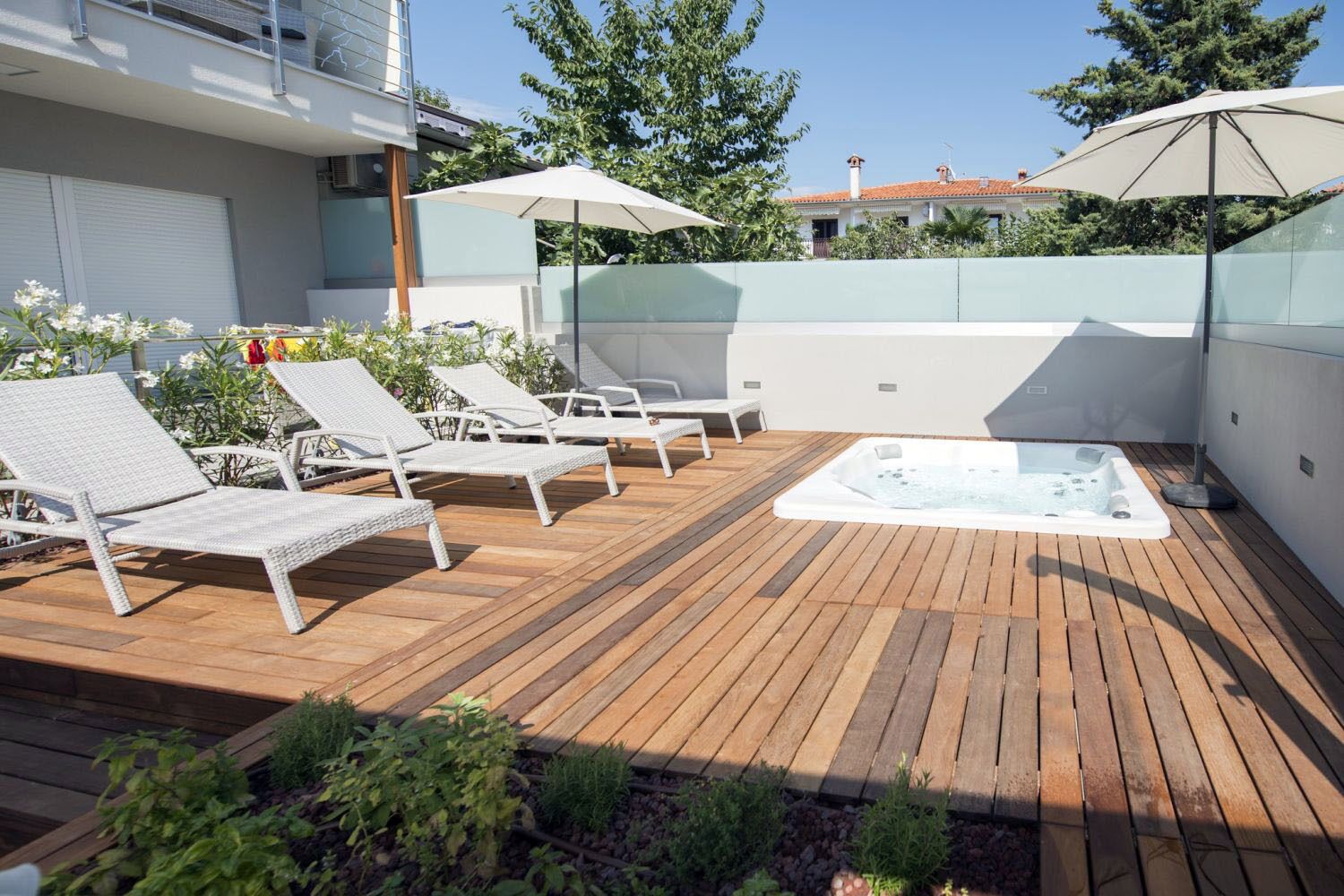 A wooden deck with lounge chairs and a hot tub.