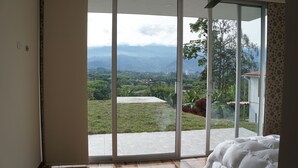A bedroom with a large sliding glass door leading to a balcony with a view of a green landscape and mountains. - Unforgettable vacations, beautiful farm with astonishing and mountains view (Circasia)
