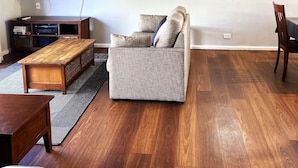 A living room with a sofa, a coffee table, a TV, and a wooden floor.