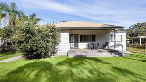 A single-story house with a front porch, a small patio, and a well-maintained lawn. - Beach Break - 22 Bay St Hat Head (Hat Head)