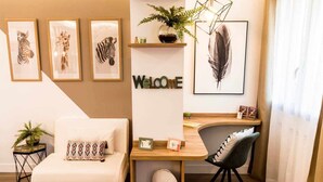 A modern living room with a white sofa, a wooden desk, and a black chair. There are framed animal prints on the wall, a 'Welcome' sign, and a feather artwork. - Zabella Salamero - Spectacular penthouse in the center of town (Zaragoza)