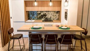 A modern kitchen with a central island, wooden cabinets, and pendant lighting. - Zabella Salamero - Spectacular penthouse in the center of town (Zaragoza)