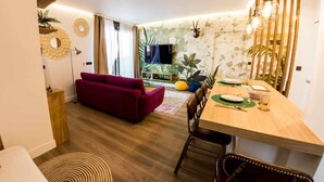 A modern living room with a red sofa, wooden dining table, and a view of the kitchen. - Zabella Salamero - Spectacular penthouse in the center of town (Zaragoza)