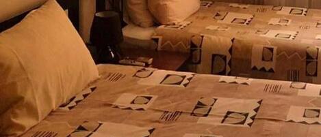 Una habitación con dos camas, cada una con colcha y almohadas estampadas.