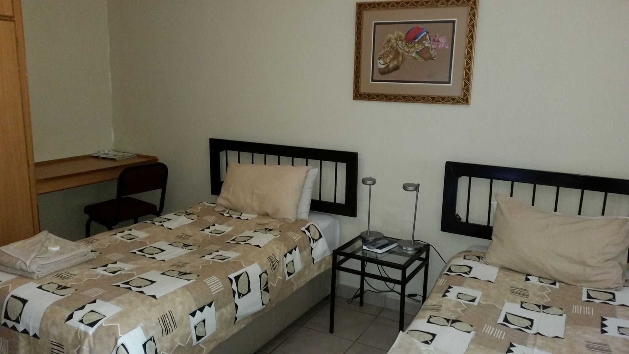 A bedroom with two beds, a desk, and a chair.