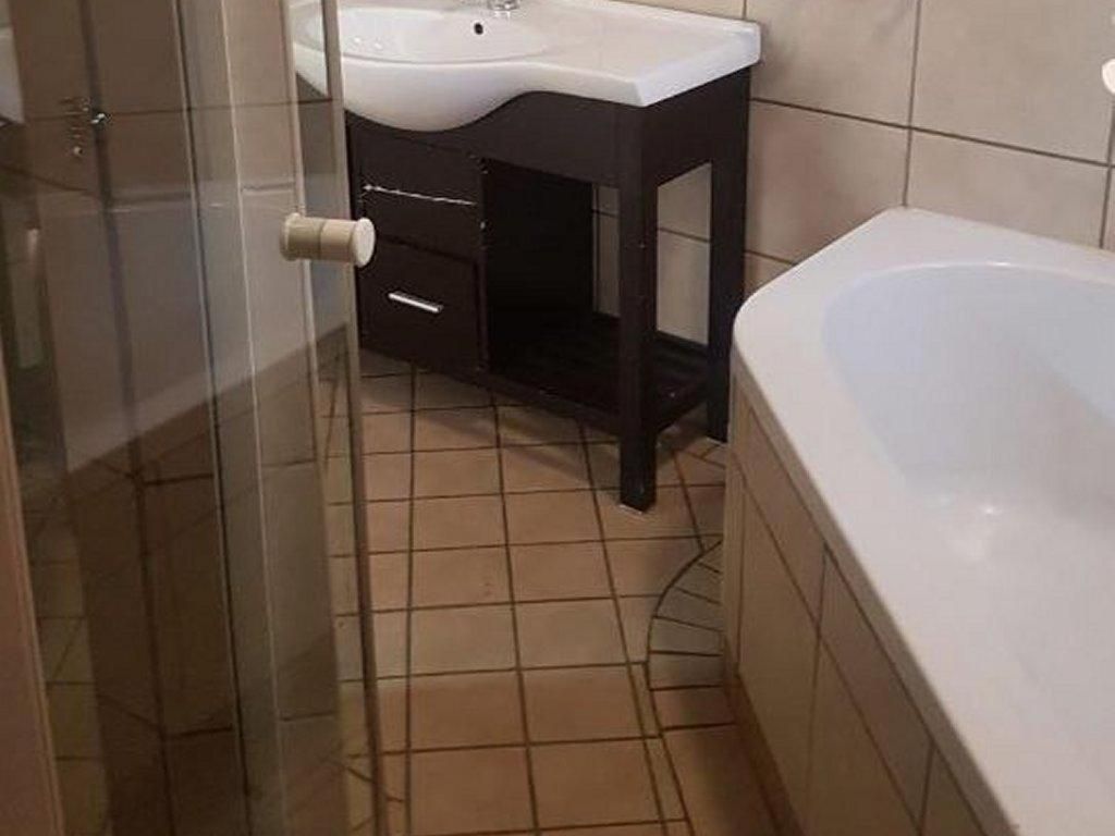 Une salle de bain avec un lavabo blanc, un meuble-lavabo de couleur foncée et une baignoire.