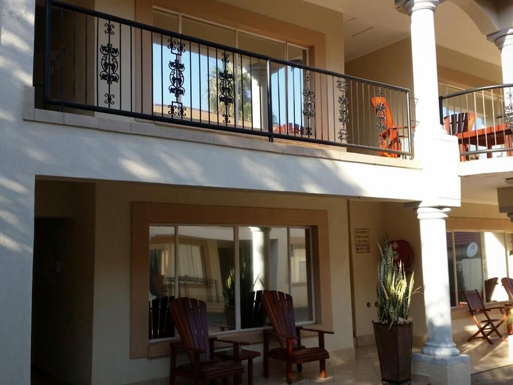 Ein Hotel mit Balkon, Sitzgelegenheit im Freien und großem Fenster.