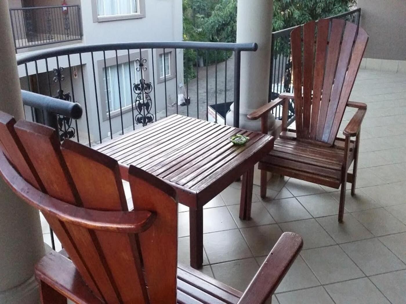 Een balkon met houten meubels, waaronder een tafel en twee stoelen.
