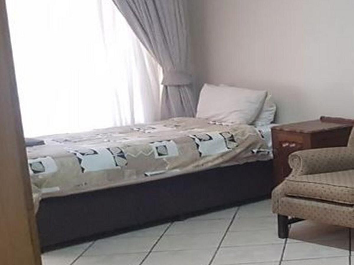 Une petite pièce simple, avec un lit, une table de chevet et une chaise.
