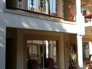 Un hotel con balcón, barandillas metálicas y una planta en maceta.