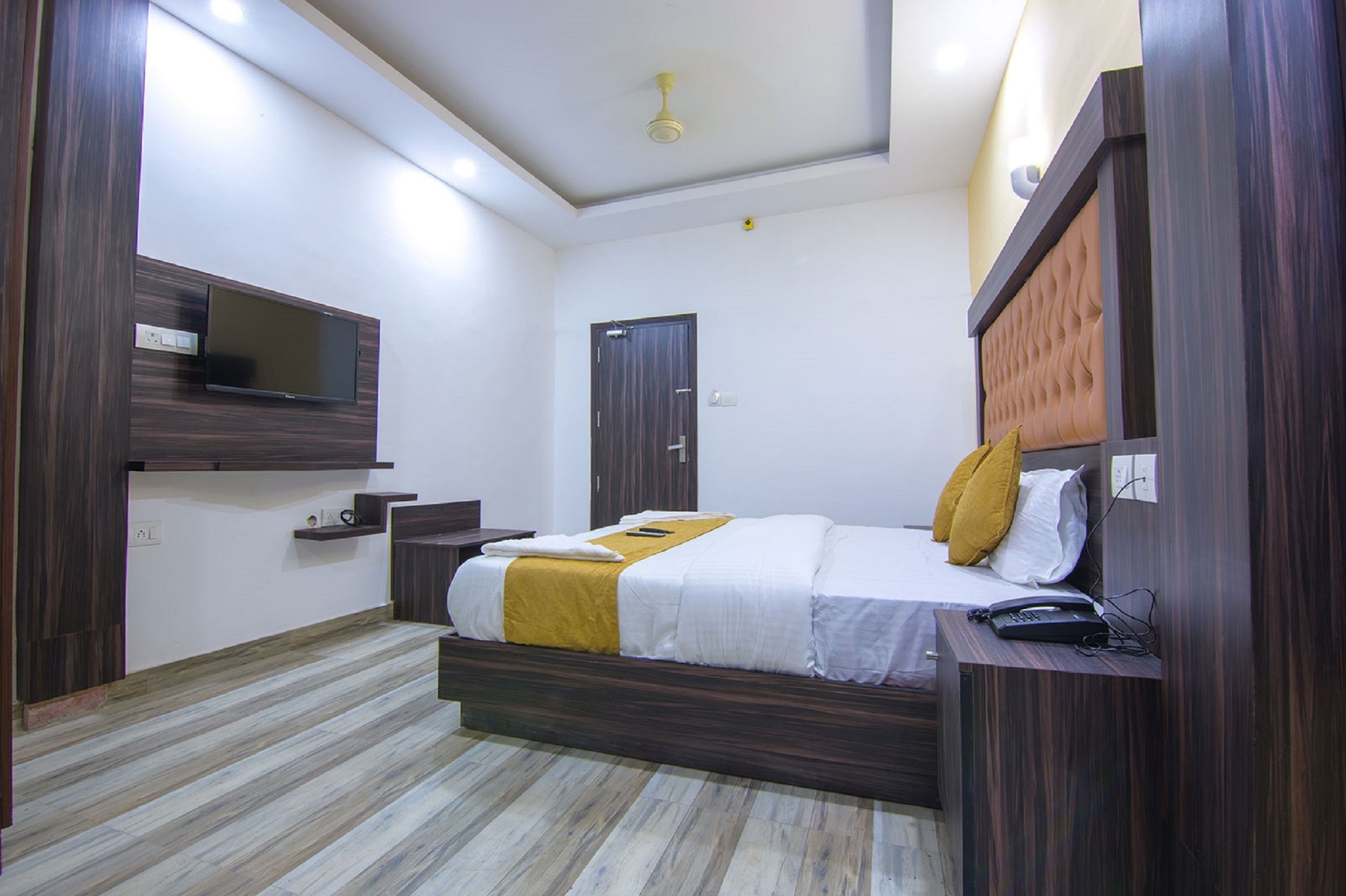 A modern hotel room with a bed, bedside table, and a mounted TV.