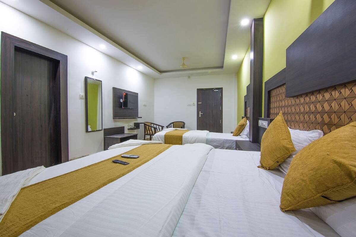 A hotel room with two beds, a desk, a chair, and a TV.