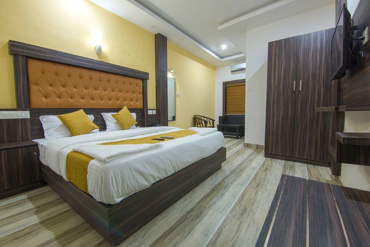 A hotel room with a large bed, wooden headboard, and a wardrobe.