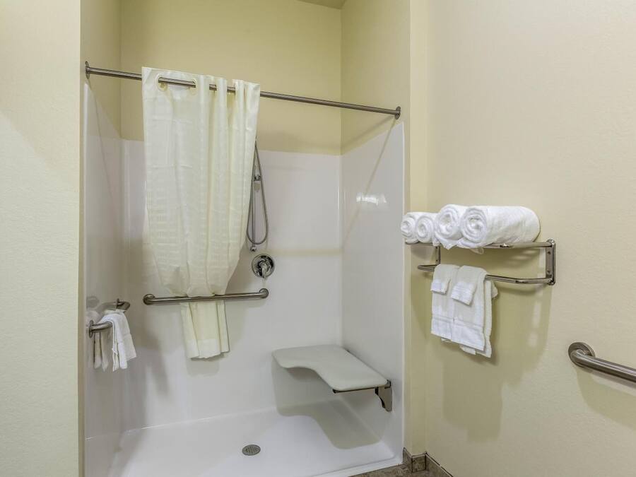 Un espace douche doté d’une porte en verre, d’un porte-serviettes avec des serviettes et d’un panneau de commande de la douche.