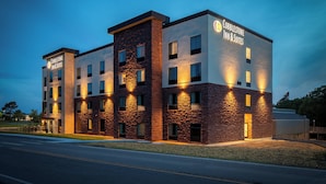 A multi-story hotel with a stone facade, multiple windows, and illuminated signage. - Cobblestone Inn & Suites - Fairfield Bay (Fairfield Bay)
