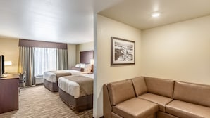 A hotel room with a large bed, a sofa, a desk, and a framed picture on the wall. - Cobblestone Inn & Suites - Fairfield Bay (Fairfield Bay)