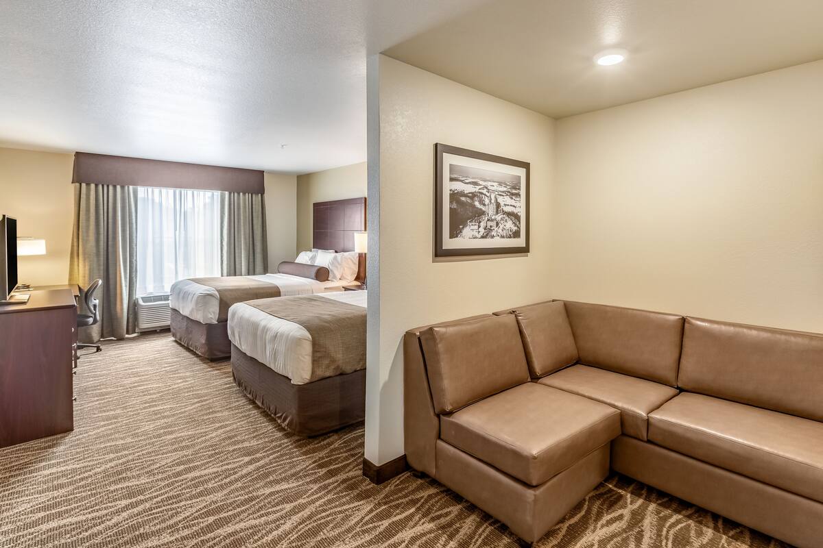 A hotel room with a large bed, a sofa, a desk, and a framed picture on the wall.