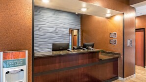A hotel reception desk with a hand sanitizer dispenser, a computer, and a phone. - Cobblestone Inn & Suites - Fairfield Bay (Fairfield Bay)