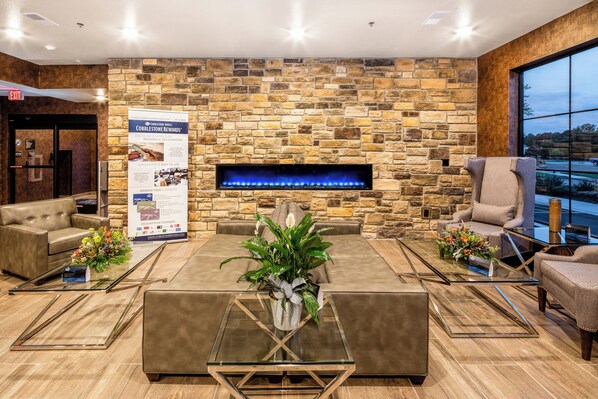 Un vestíbulo moderno con una pared de piedra, una chimenea, sofás de cuero y una mesa de centro de vidrio.
