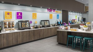 A modern breakfast area with a sign reading "TOP IT BREAKFAST," featuring various food options like donuts, sandwiches, and waffles. - Home2 Suites by Hilton Nashville Downtown Convention Center (Nashville)