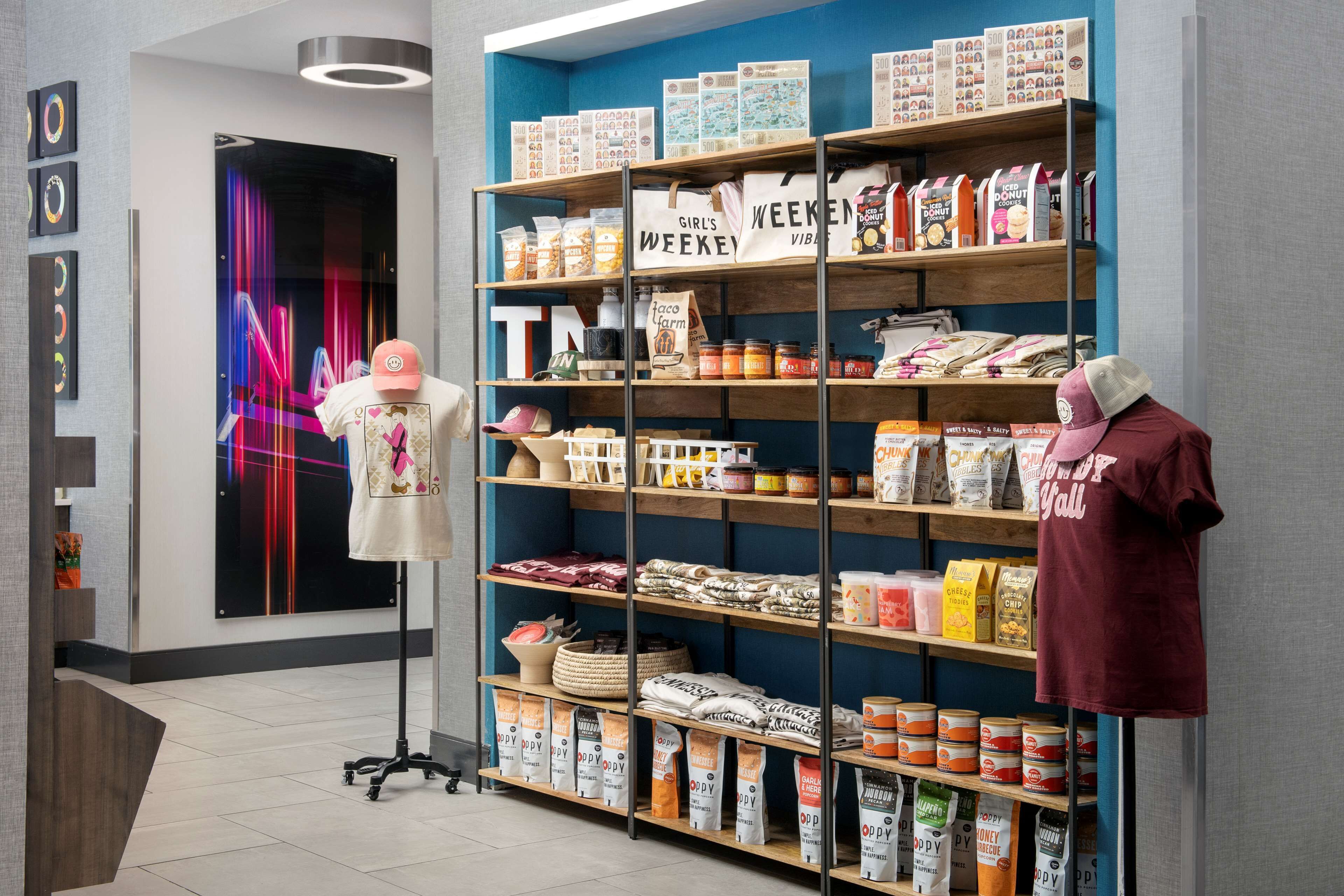 A store with shelves stocked with snacks, a mannequin with a cap, and a neon sign.