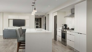 A modern kitchen with a central island, built-in appliances, and a grey sofa in the adjacent living area. - Home2 Suites by Hilton Nashville Downtown Convention Center (Nashville)