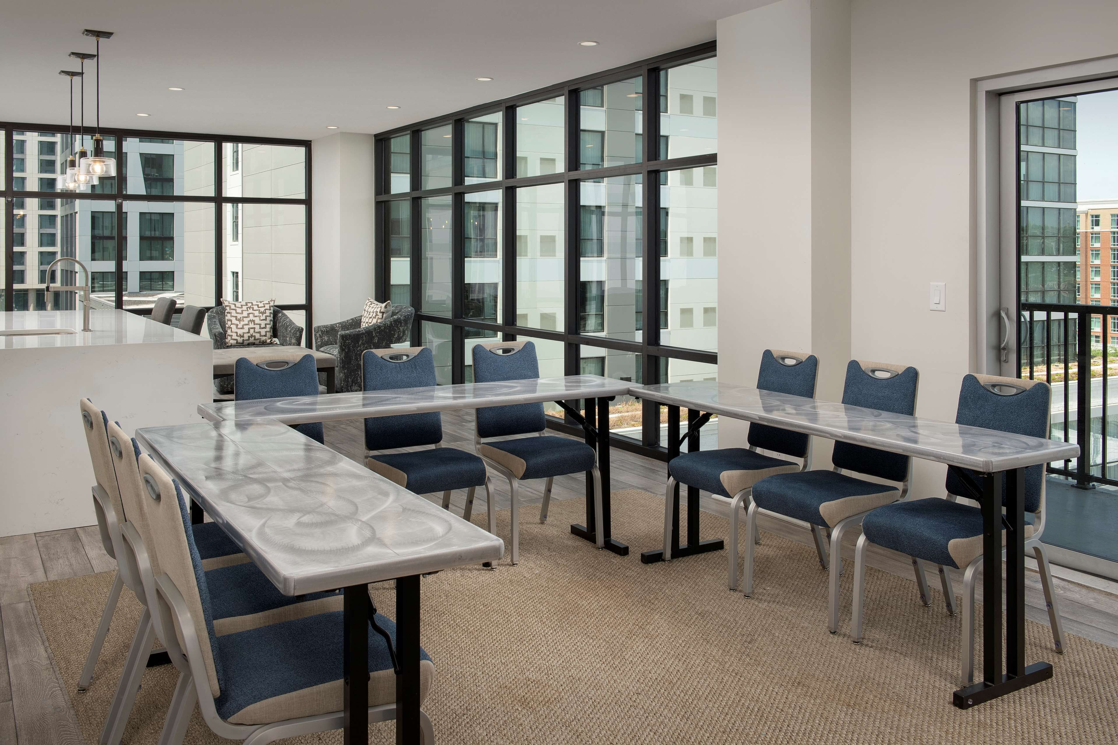 Ein moderner Konferenzraum mit Glaswänden, einem langen Tisch und blauen, gepolsterten Stühlen.